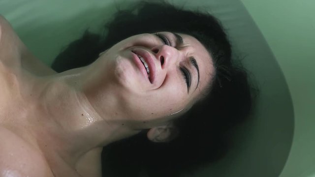 abused woman lying in the bathtub screams in despair