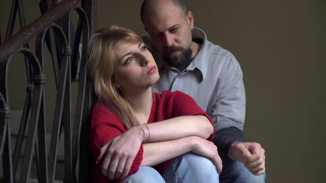 depresse woman sitting on the stairs is reached by the boyfriend comforting her