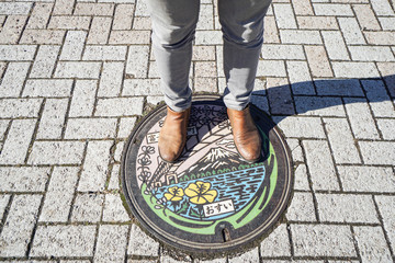 Naklejka premium man stand on manhole cover taken at Kawaguchiko Japan on 4 December 2016