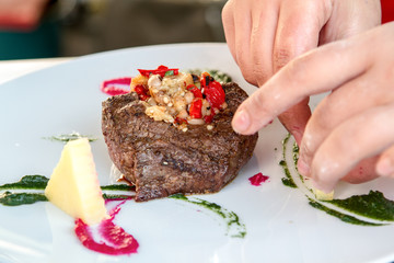 Chef is decorating meat with steamed vegetables