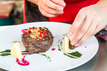 Chef is decorating meat with steamed vegetables