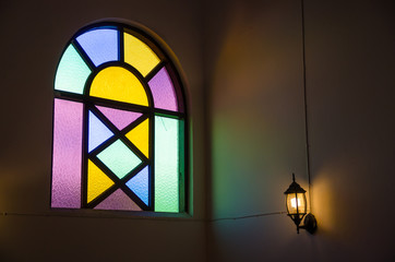 colorful glass window with lamp light on wall