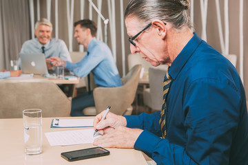 Obraz premium Starszy biznesmen i zespół pracujący w kawiarni