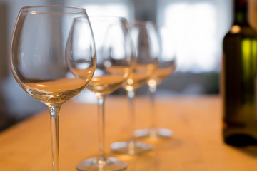 An intimate wine tasting at a winery with a bottle of white wine and 4 wine glasses on a wooden bar table