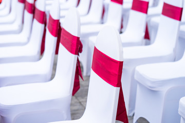 Event chairs with white and red decoration lined up in row