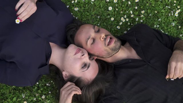 pair of lovers lying on the grass chatting amiably