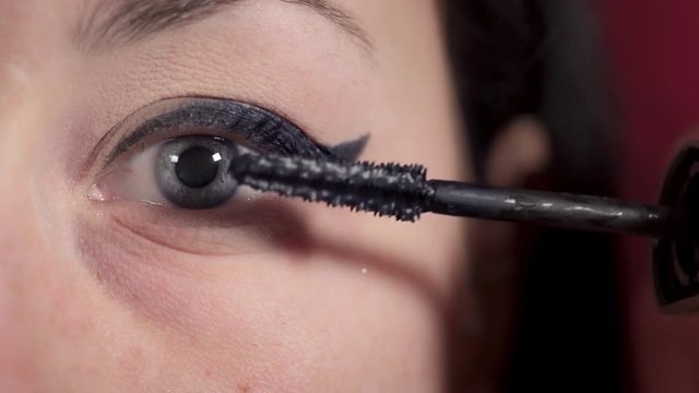 macro-blue eyes woman putting mascara