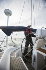 Man Steering Wheel Of Yacht In Sea During Sunset