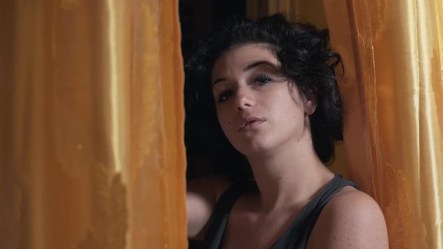 sexy young woman near the window touches hair flirting with the camera