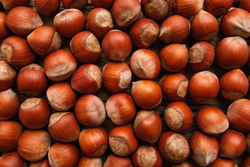 Pile of ripe hazelnuts flat lay. Top view on lot of filbert nuts, brown autumn background. Fall, harvest, vitamin, health concept