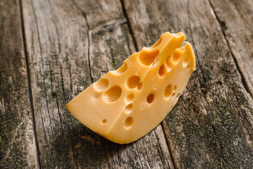 Slice of fresh cheese on old wooden background. Delicious gourmet snack for wine. Delicatessen, appetizer, natural food, luxury lifestyle concept