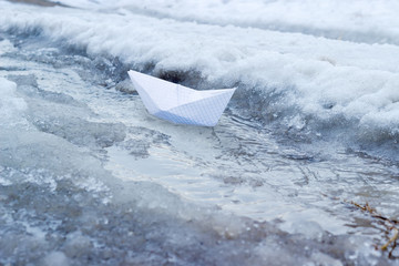 Paper boat in the stream of melt water