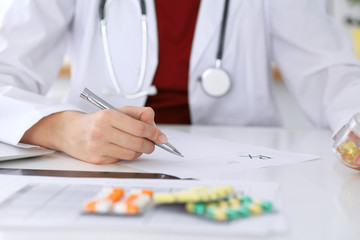 Female medicine doctor fills up  prescription form to patient closeup. Panacea and life save, prescribe treatment, legal drug store, contraception concept