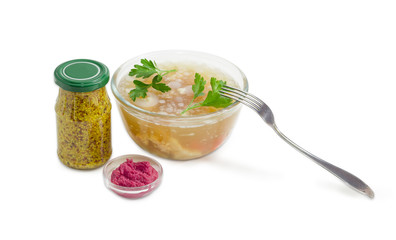 Pork jelly in glass bowl with different seasoning and fork