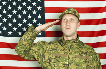 Serios  young soldier salute against  American flag. Portrait 