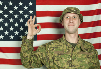 Smiling soldier stand against  American flag  with international sjgn everything well