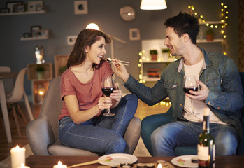 Man feeding woman sushi on a date .