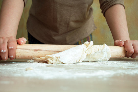 woman rolls  dough with a rolling pin