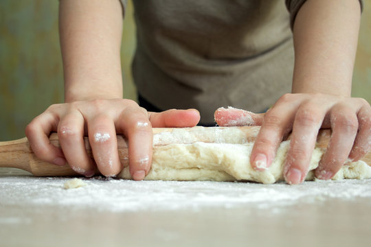 woman rolls  dough with a rolling pin