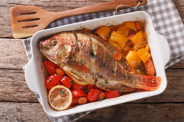 Baked tilapia with sweet pepper, carrot, lemon and thyme close up. horizontal top view