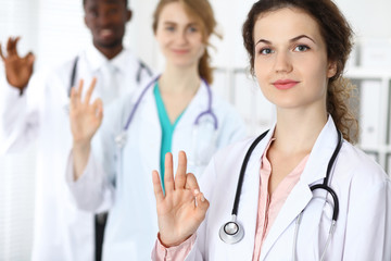 Fototapeta premium Medical team of confident doctors showing Ok sign and ready to help. Medicine and health care, insurance concept