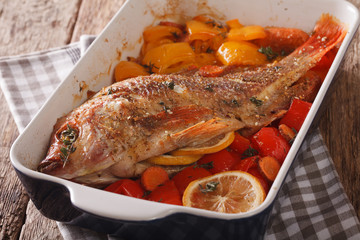 Baked tilapia with sweet pepper, carrot, lemon and thyme close up. horizontal