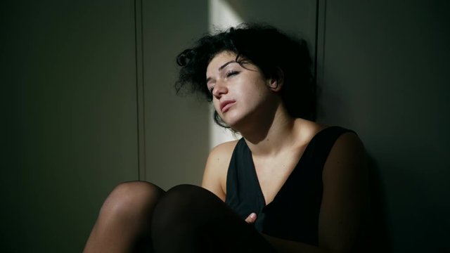 sad and helpless woman sitting on the floor in the dark