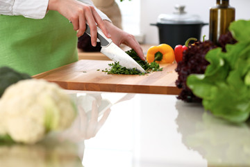 Closeup of human hands cooking vegetables salad in kitchen on the glass table with reflection. Healthy meal and vegetarian concept