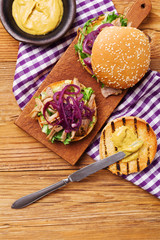 Burger with meat of duck with red onion and lettuce.
