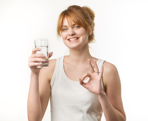 sporty woman over gray background holding glass of water