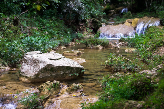Big stones in flowing river at the mountains of green tropical jungle forest