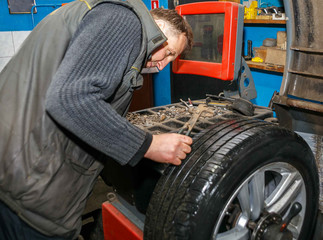Professional auto mechanic makes balancing vehicle wheels