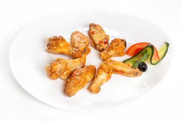 Plate of fried golden chicken wings and legs isolated at white background.