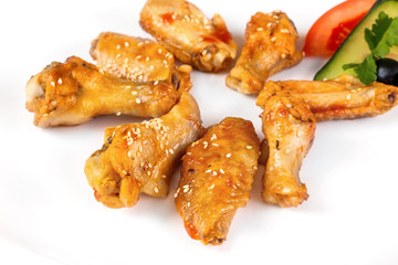 Plate of fried golden chicken wings and legs isolated at white background.