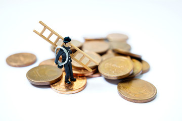 Glücksbringer Schornsteinfeger mit Leiter steht auf Kleingeld als Glückssymbol für Wohlstand und Reichtum
