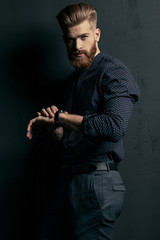 Stylish handsome bearded man hipster with wristwatch looking at camera