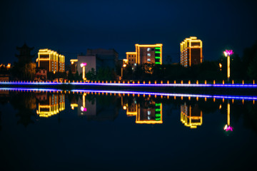 Night city, park in the Hunchun, China. Reflection lights in the water.