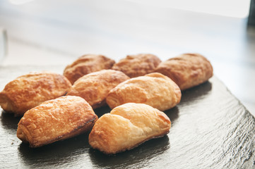 Set of sausage croissant on black plate.