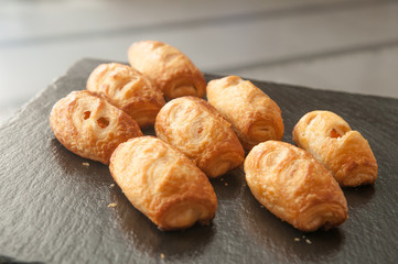 Set of sausage croissant on black plate.