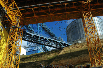 industrial crane, granary and flying birds