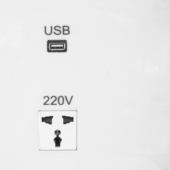 Female connector plug and USB charger port on white wall.