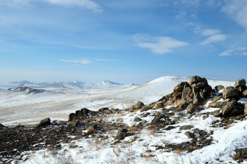 Mountain winter landscape. with high hills Olkhon offers beautiful views of Lake Baikal, covered with ice. Snow-capped mountains on the horizon. Sunny day. Photo partially tinted.