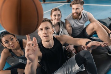 Sporty young people looking at man balancing ball on finger