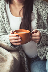 Woman with beautiful manicure holding a orange cup of cocoa
