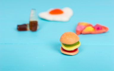 Jelly candies in the form of a burger, pizza and drink on wooden table