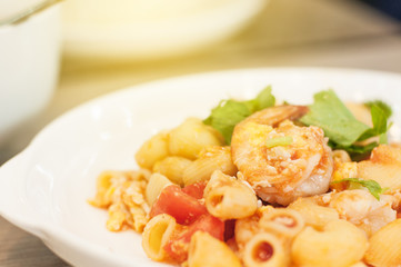 Shrimp macaroni in white plate with light flare.