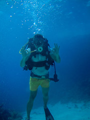 Fototapeta na wymiar Underwater shoot of a man diving looking at the camera and showing ok
