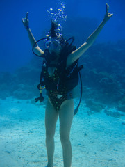 Underwater shoot of a woman diving, puts her hands up and showing peace signal