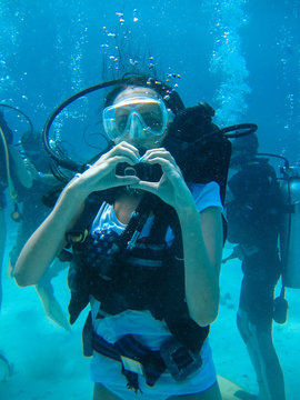 Underwater shoot of a woman diving and showing love signal