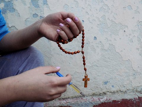 Young women holding rosary and drugs injection in palms, young girl using drugs